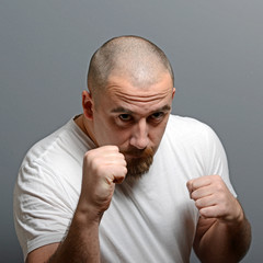 Portrait of a angry man holding fists against gray background