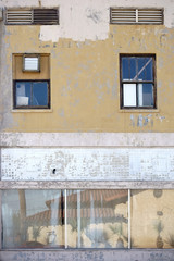 Fototapeta premium Vergilbte Fassade / Ein heruntergekommenes Wohn und Geschäftshaus mit einer vergilbten Fassade sowie Spiegelungen in den Schaufenstern.