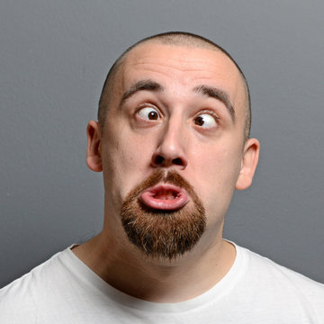 Portrait of a man making funny face against gray background