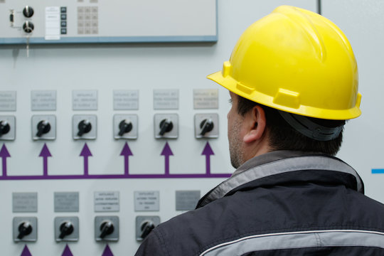 Technician reading instruments in power plant control center