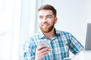 Happy man using smartphone and looking away
