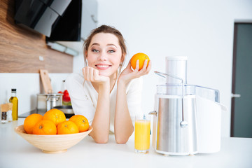 Beautiful woman using juicer for making orange juice