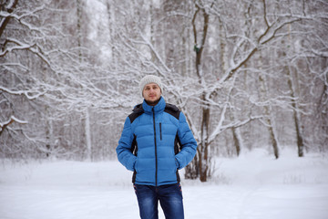 Fototapeta na wymiar man in turn blue to the winter sport jacket stands in the snow f