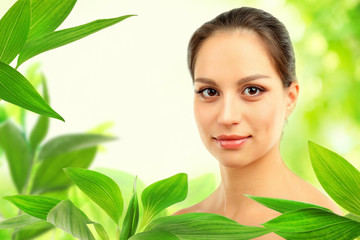 Portrait of young beautiful woman, on green nature background with leaves