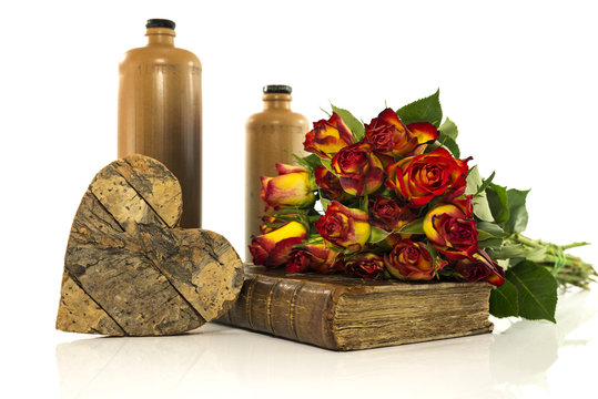 stone bottle with old book and red roses