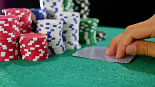 A poker gambler peeks at his cards and bets