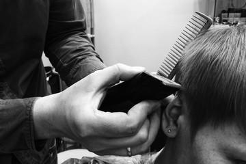 Hairdresser trimming woman short hair with trimmer close up