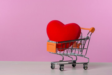 Big red heart in a shopping cart. Concept for buying love