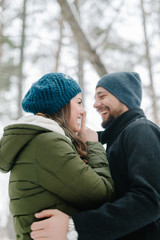 Fototapeta premium Cute young hipster couple having fun in winter park warming eachother on a bright day hugging each other and smiling 