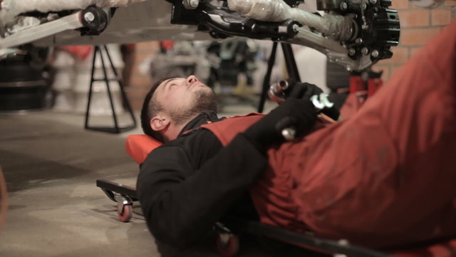 Young mechanic in red overalls engaged manual assembly machines