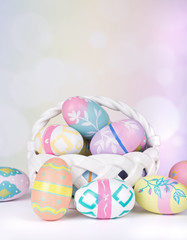 Fototapeta na wymiar Assortment of Colorful Easter Eggs and Basket on a Bright Background