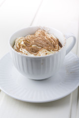 Hot chocolate garnished with whipped cream and cocoa powder.