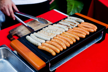 Fresh sausage and hot dogs grilling outdoors on a gas barbecue g