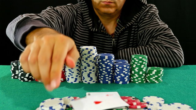 A gambler at a poker table makes a challenge gesture