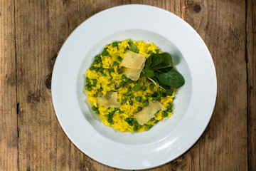 Leek, garden pea and saffron risotto looking down on plate. French restaurant prepared cuisine with bright yellow rice
