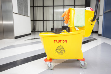 Yellow mop bucket and set of cleaning equipment in the office