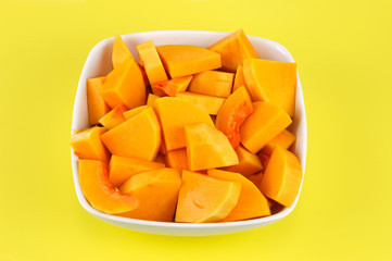 chopped butternut squash in the bowl on yellow background