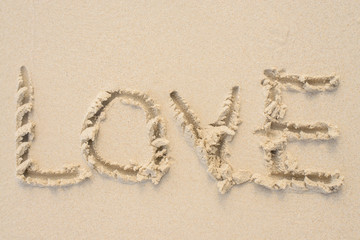 Love message written in sand. Beach background. Top view