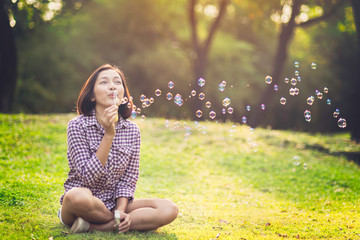 beautiful young woman blowing bubble in the park