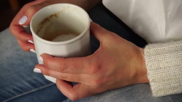 Woman holds coffee mug warming her hands closeup 4K