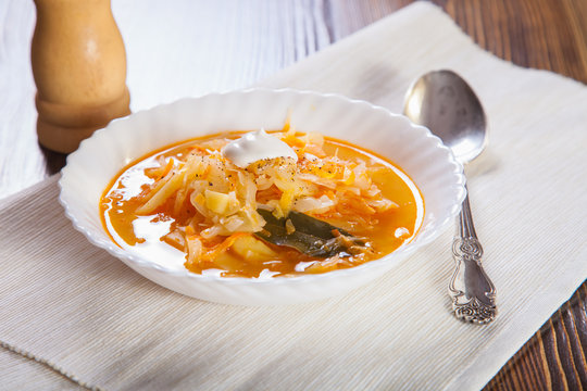 Russian cabbage soup in a plate on a table, selective focus
