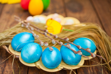 Fototapeta na wymiar Easter colored eggs and willow on a table, selective focus