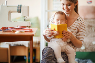 Mother and baby reading a book together at home.