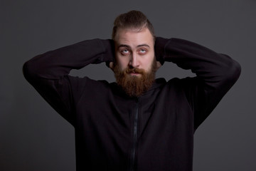 young man with a beard covers his ears