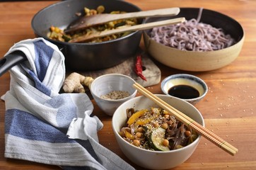 Black rice noodles and stir fried vegetables in a bowl, with soy sauce