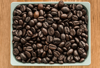 brown coffee beans in cup on wood background