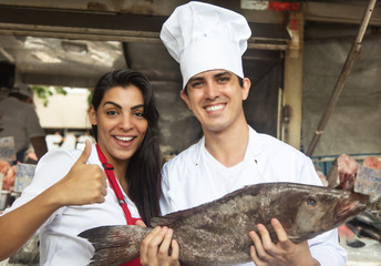 Koch mit Verkäuferin beim Fischkauf auf dem Markt