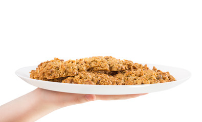 Hand holding plate with oatmeal biscuits.