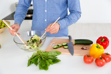 Salad in glass bowl made by male on the kitchen