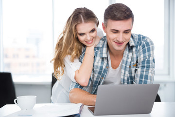 Happy couple using laptop and surfing in internet