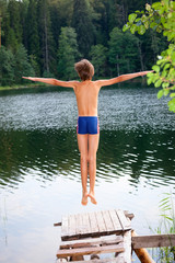 Boy jumping into forest lake