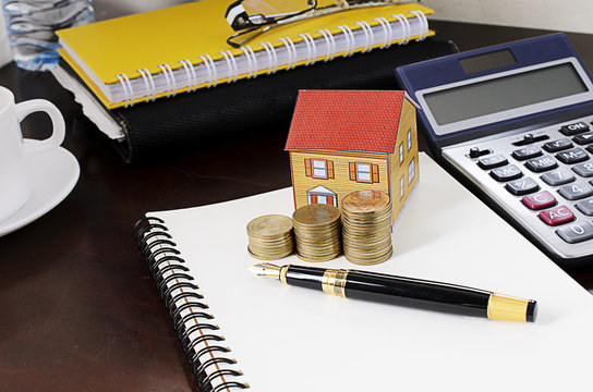 business fountain pen with coins stack and paper house and calcu