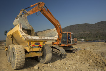 Image of an excavator loading dirt on to a truck in construction