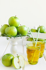 Apple juice from green apples on a white wooden background