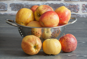 Différentes variétés de pommes dans une écumoire sur fond sombre