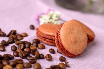 macaroon on a napkin with coffee beans scattered on a purple napkin closeup