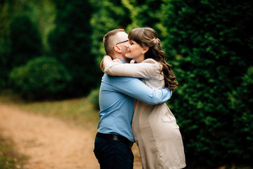 Fototapeta premium Pregnant beautiful woman and her handsome husband lovely hugging in autumn park.