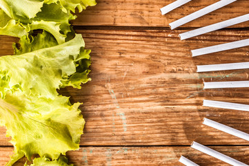 Cigarettes and lettuce on wood background. Concept of healthy life without addiction