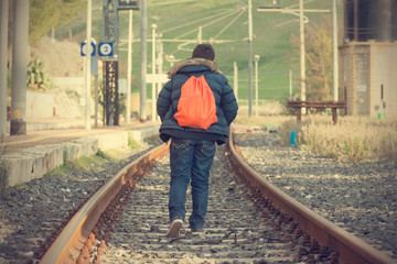 Teenager walking away on railway. Concept of escape and adventur - obrazy, fototapety, plakaty