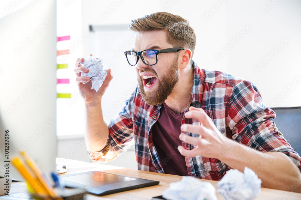 Wall mural angry crazy designer yelling and crumpling paper on his workplace