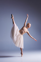 Naklejka na ściany i meble Young beautiful ballerina dancer dancing on a studio background