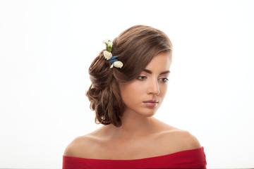 Young adorable brunette woman in red blouse with low bun hairstyle and flower headpiece showing trendy makeup