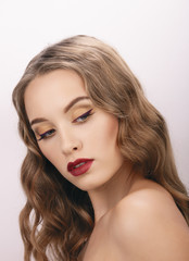 Fototapeta premium Closeup beauty portrait of young elegant blonde woman with fashionable trendy makeup wavy hairstyle posing on white studio background 