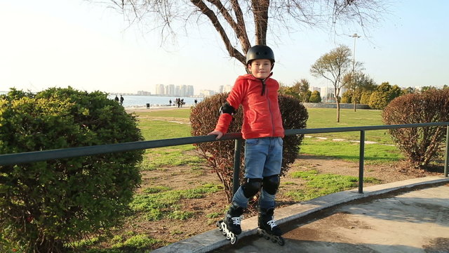Happy little boy training in sunny day on roller skates