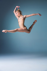 Fototapeta premium Young beautiful modern style dancer jumping on a studio background