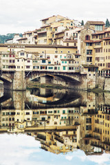 Naklejka premium Ponte Vecchio and historic buildings are mirrored in the Arno